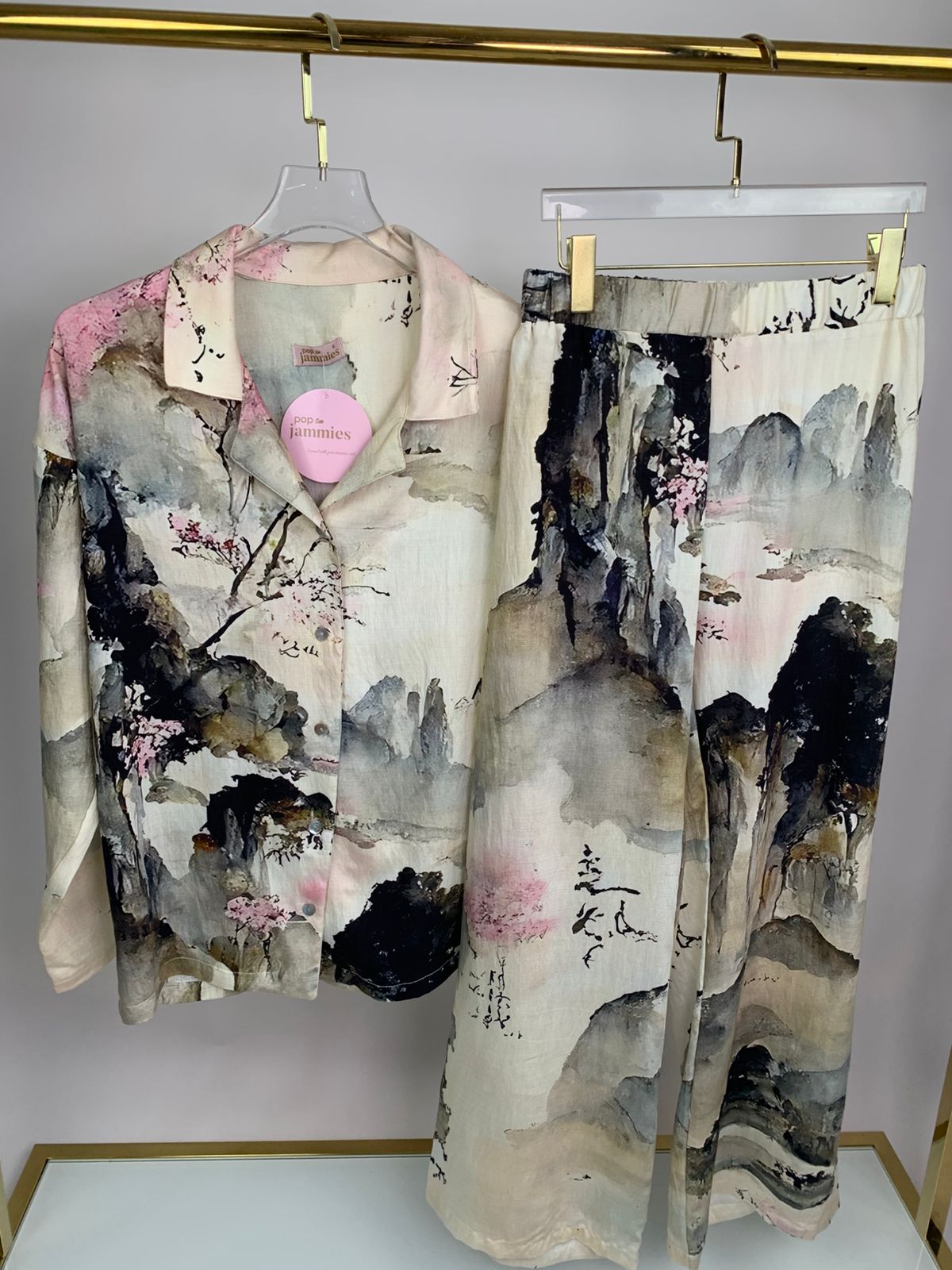 Traditional Japanese kimono with artistic design on a hanger against a neutral background