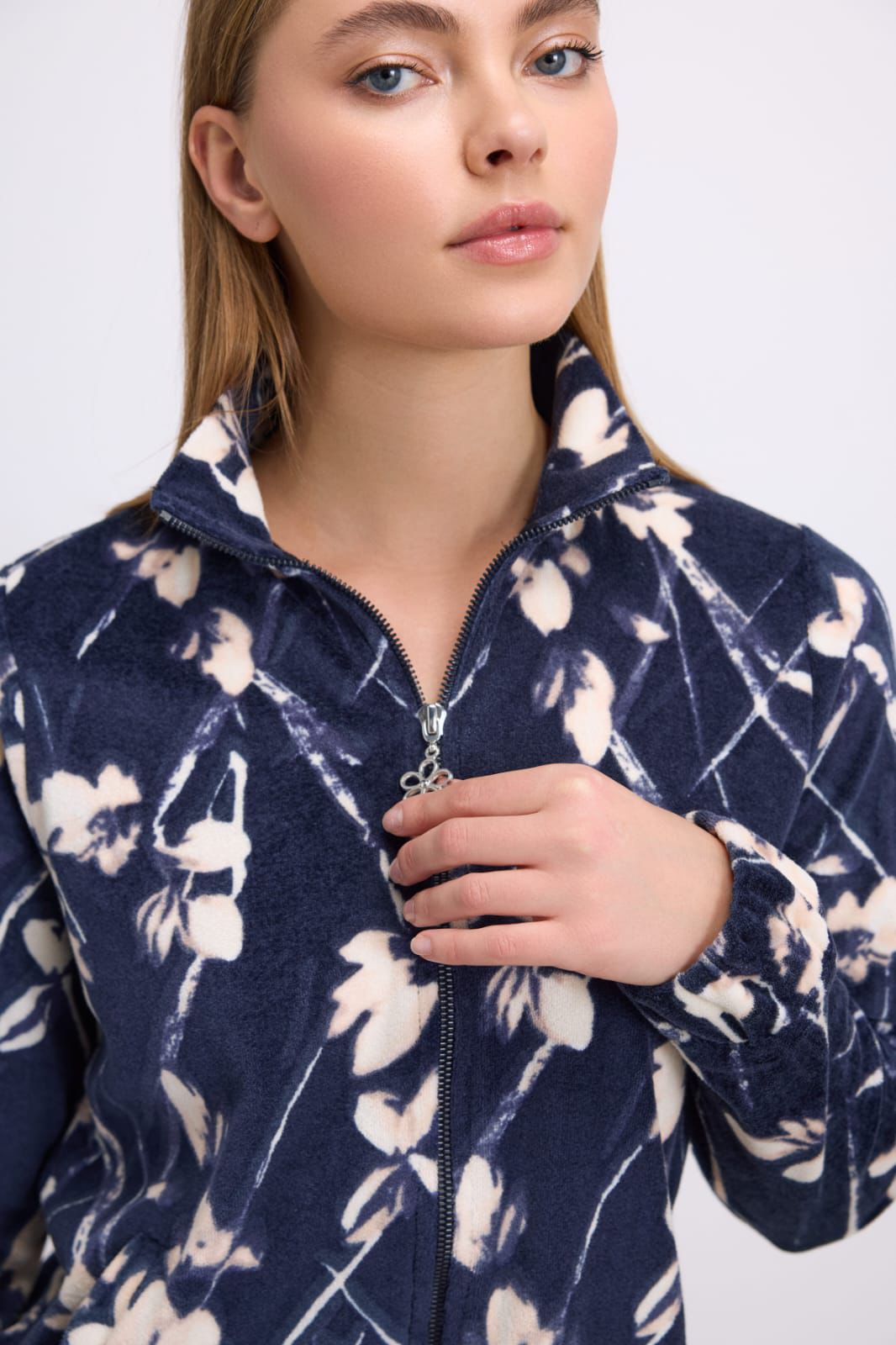 Woman wearing a navy blue fleece jacket with white floral pattern on a plain background