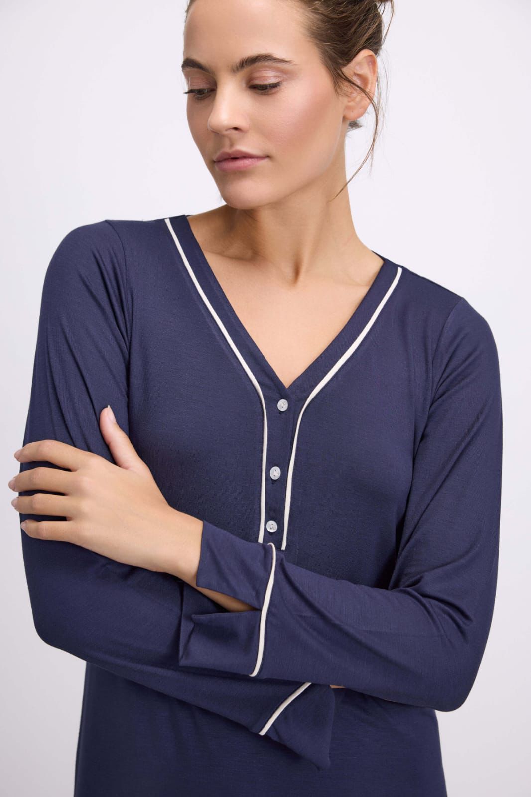 Woman wearing a navy blue nightshirt with white trim on a white background