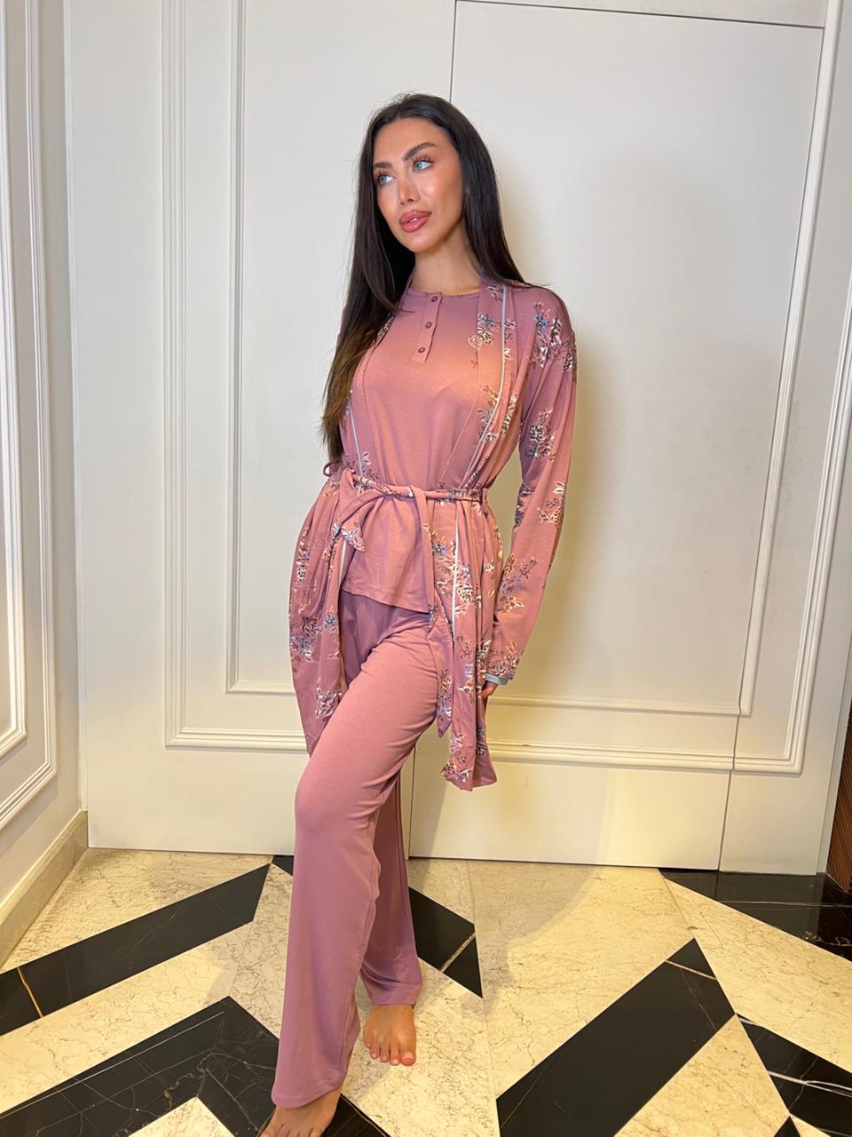 Woman in a pink outfit standing in a room with white walls and black and beige floor.
