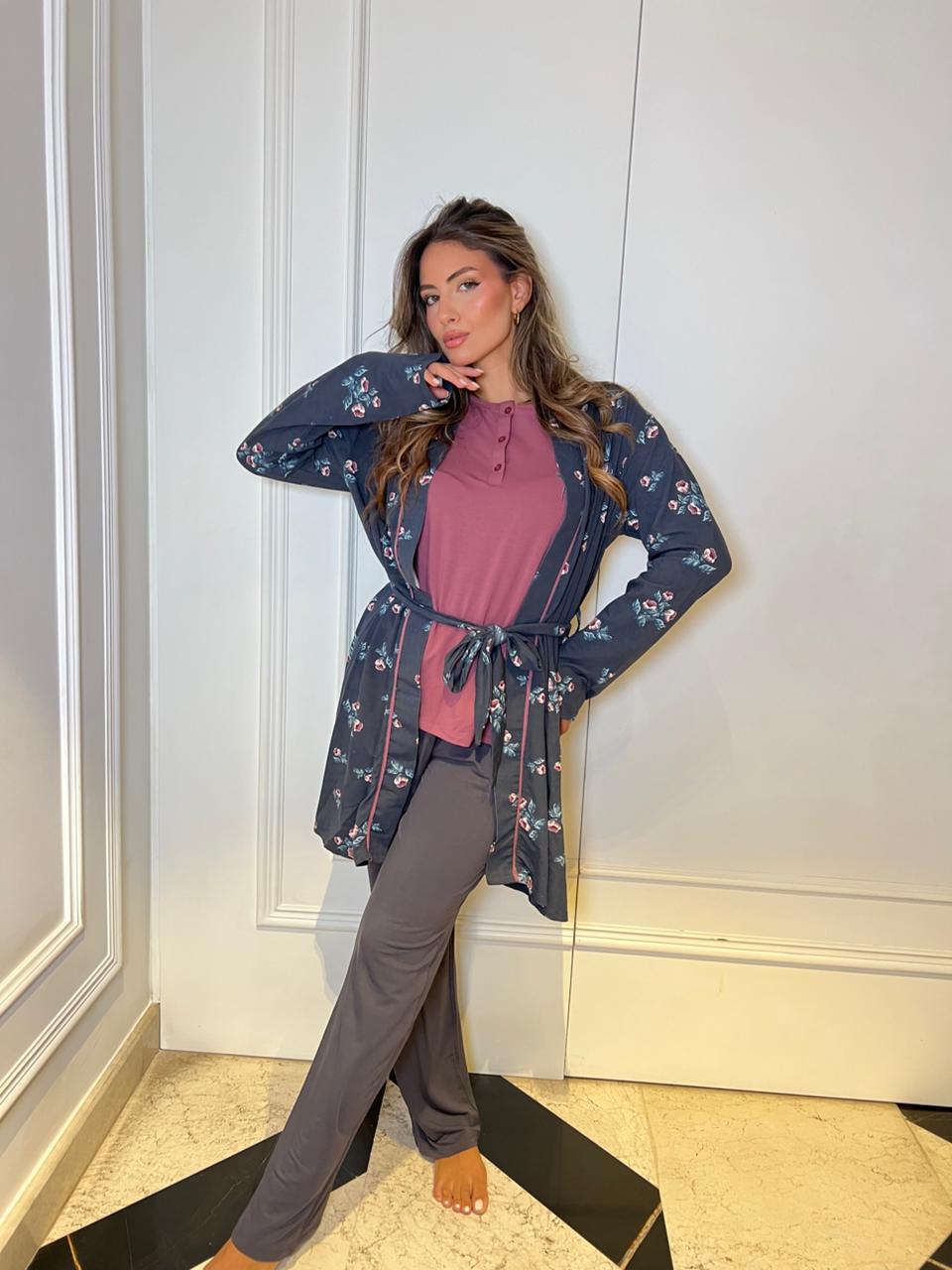 Woman wearing a floral kimono-style jacket over a pink top and gray pants in an indoor setting.