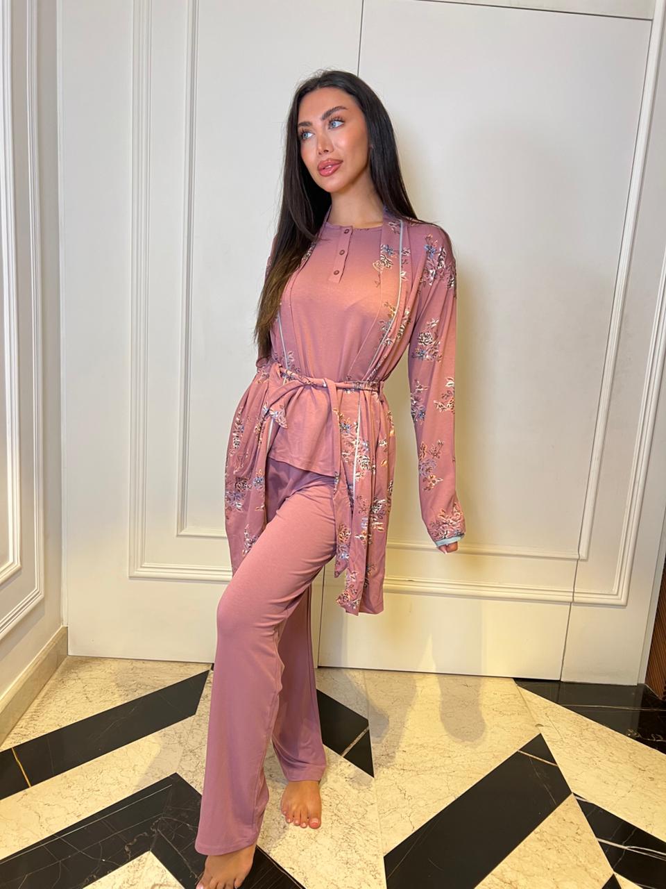 Woman in a pink outfit standing in a room with a white paneled wall and black and white tiled floor.