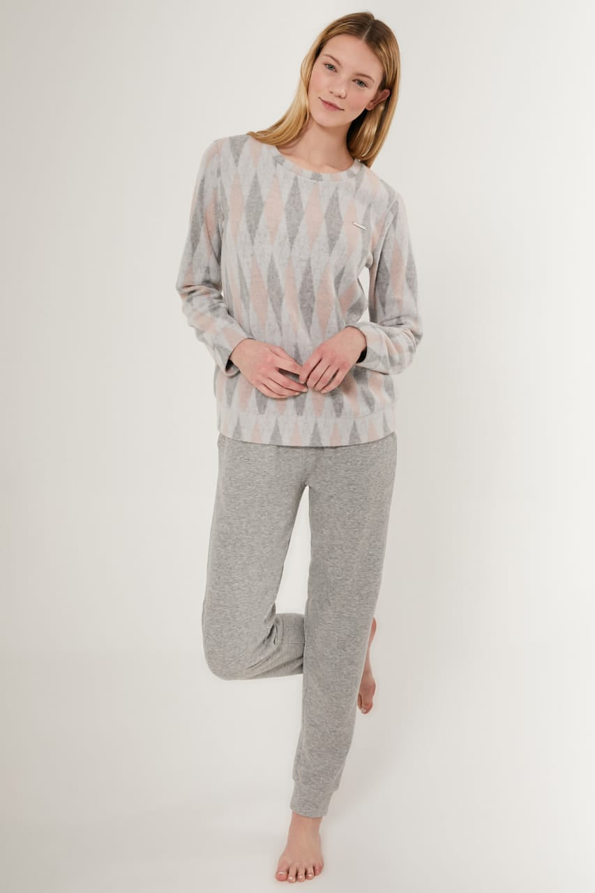 A female model standing and posing in a gray two-piece pajama set with a geometric pattern on the top and solid gray pants.