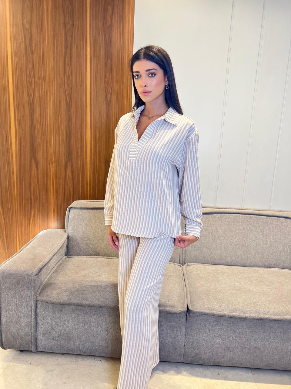 Woman in a striped outfit standing in a room with a couch and wooden wall.