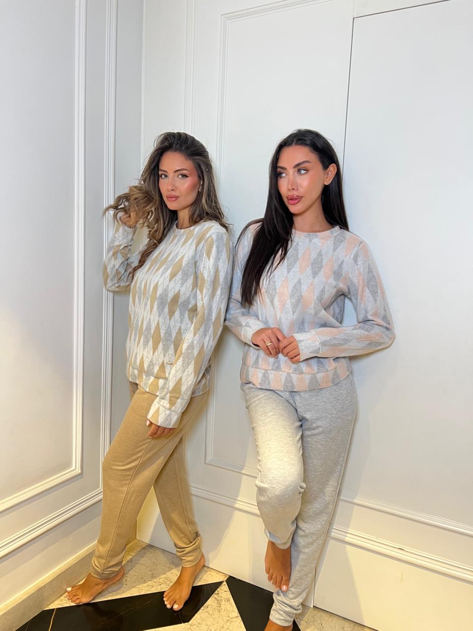 Two women wearing matching patterned tops and pants standing in a room with white walls.