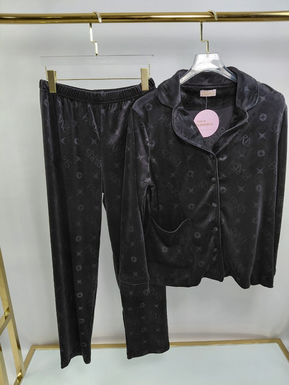 Black pajama set with matching jacket and pants on hangers against a white background.