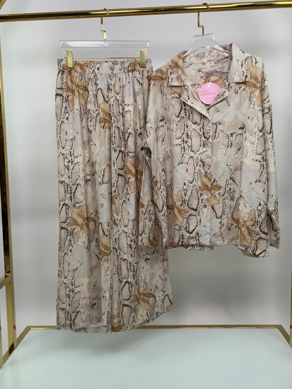 Snake print shirt and pants on hangers against a white background
