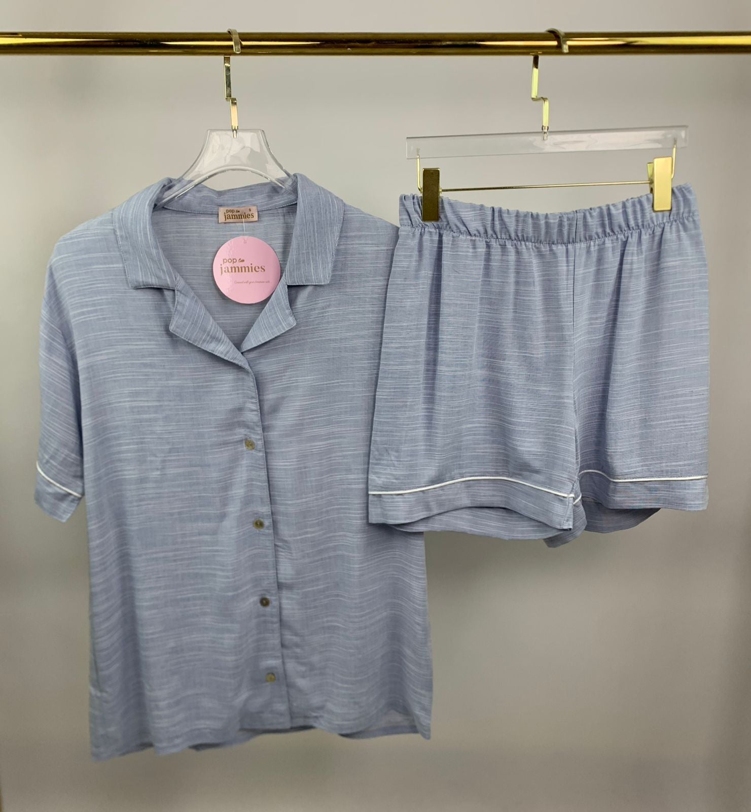 Blue striped pajama set on hangers against a neutral background
