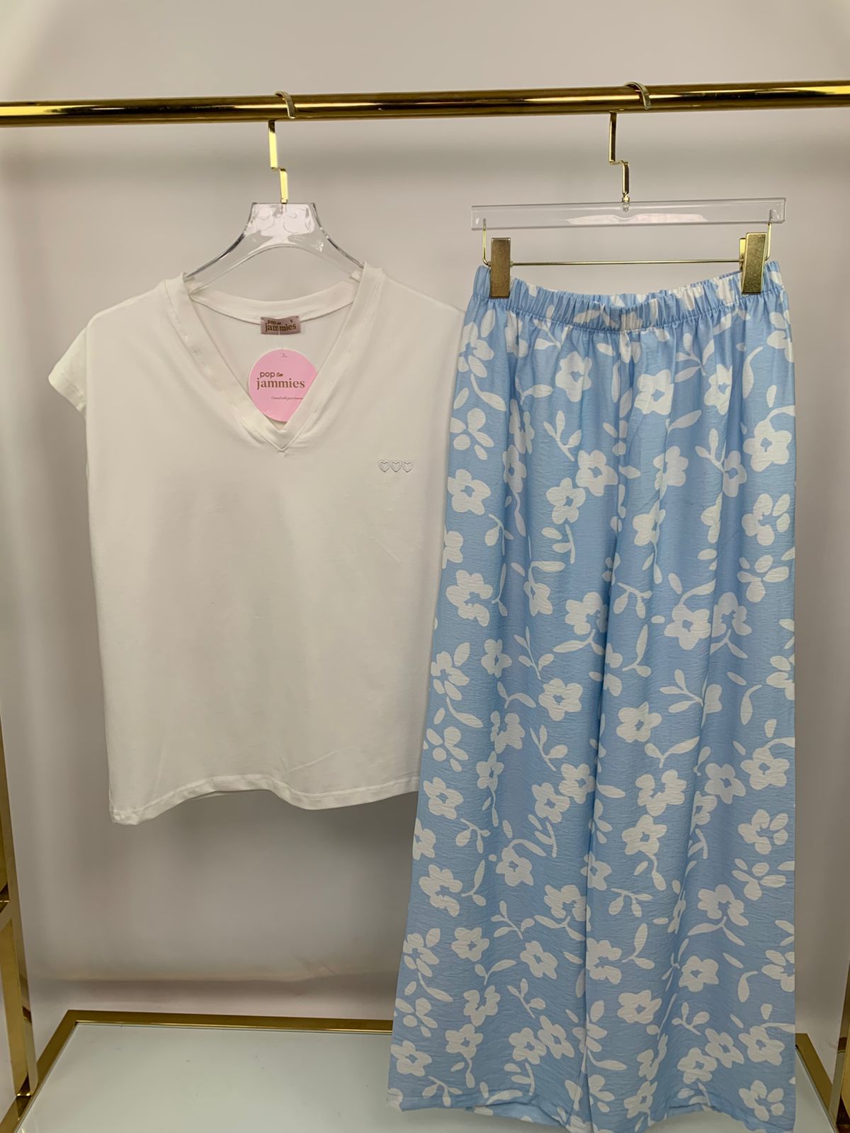 2-piece women’s pyjama set - pajama set - summer pajama - White t-shirt and blue floral pants hanging on a rack.