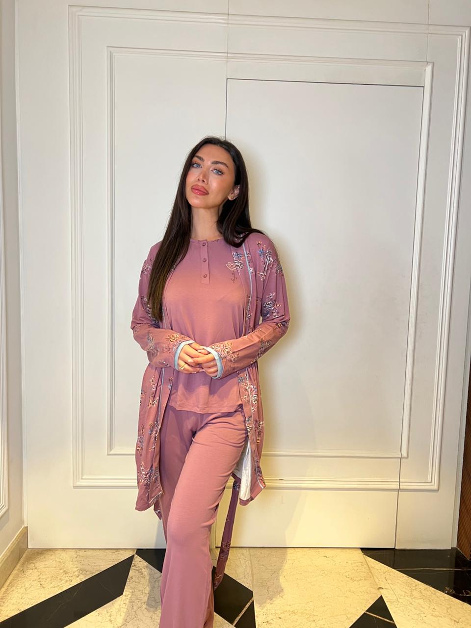 Woman in a pink outfit standing against a white wall.