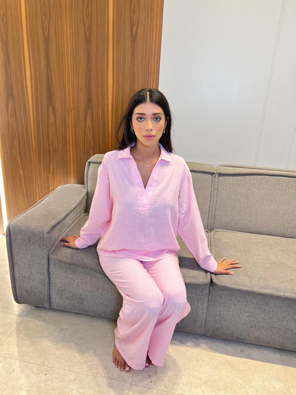 Woman in pink pajama set sitting on a gray couch in a modern room.
2-piece women’s pyjama set featuring a cozy top and matching pants