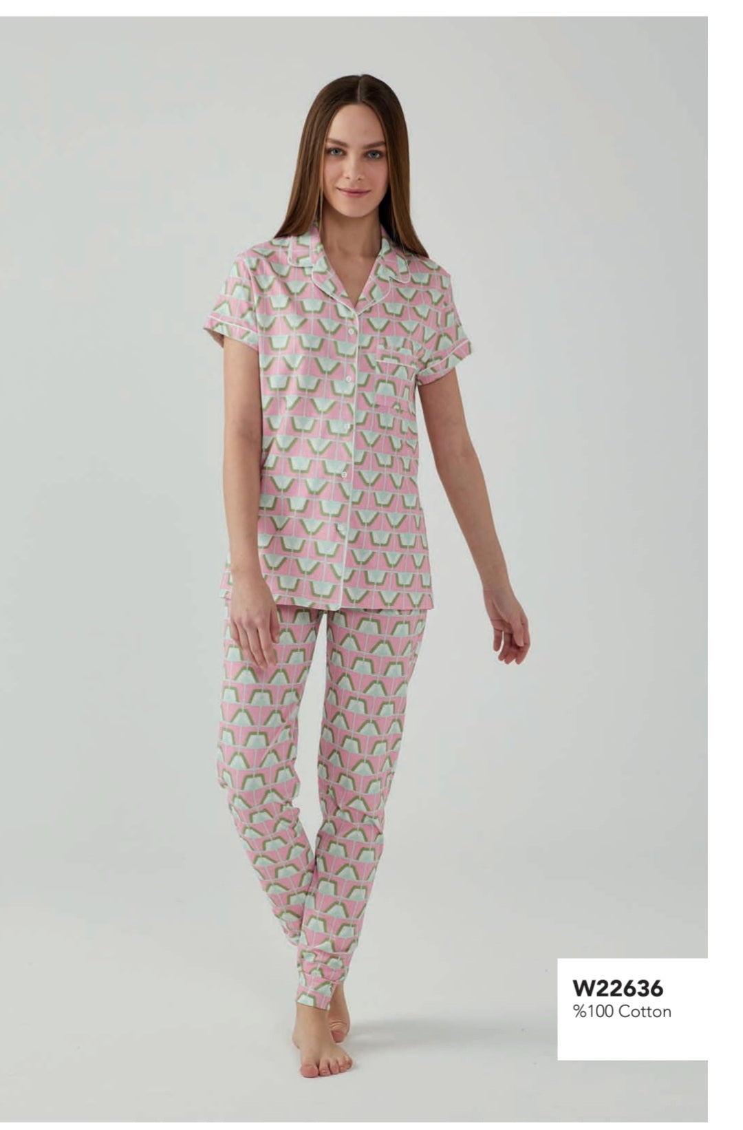 Model wearing a Popjammies pink geometric pyjama set, featuring a short-sleeve button-down top with a pocket and matching pants, walking barefoot.