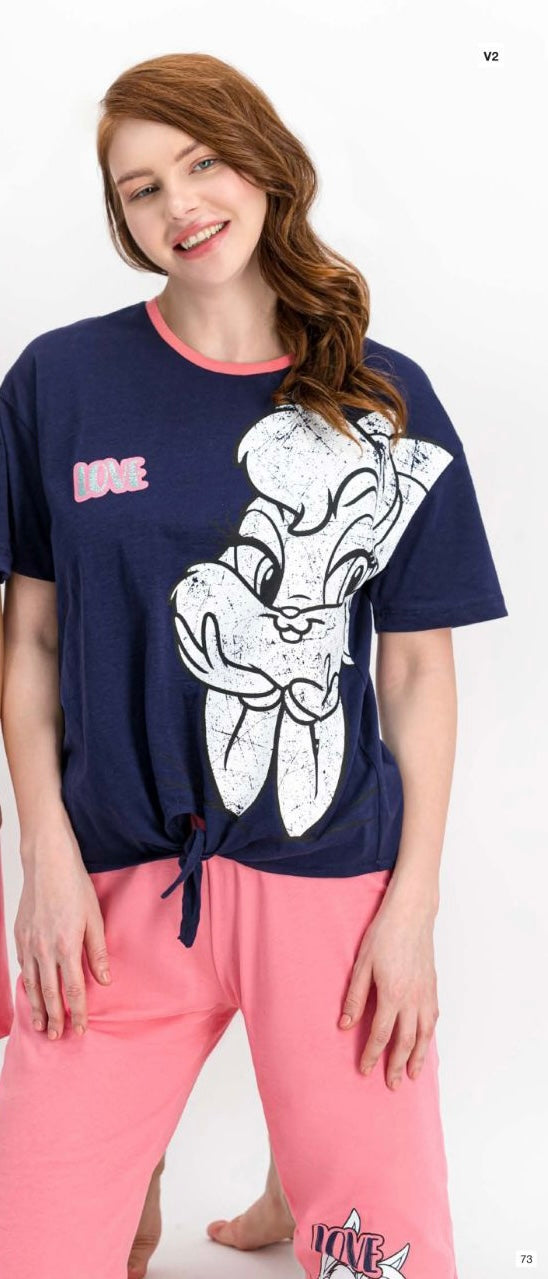 Woman wearing a navy short-sleeve top with a white bunny print and tie-front detail, paired with pink capri pantacour with a bunny graphic