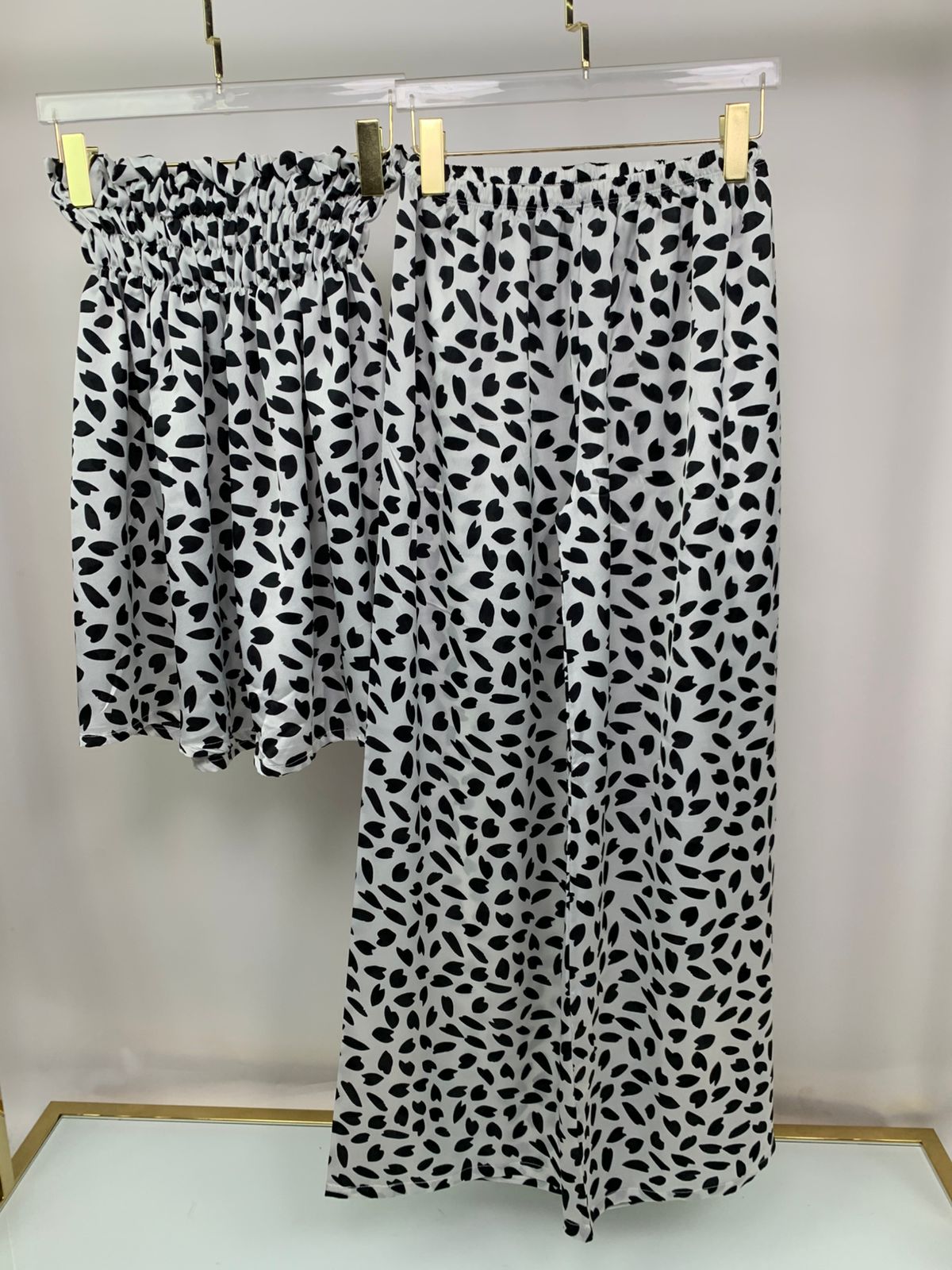 2-piece women’s pants pyjama set - pajama - pajama set - women pajama - summer pajama - Black and white patterned pants hanging on a rack against a plain background