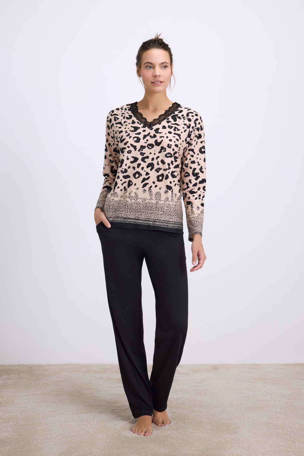 Woman wearing a leopard print top and black pants on a white background