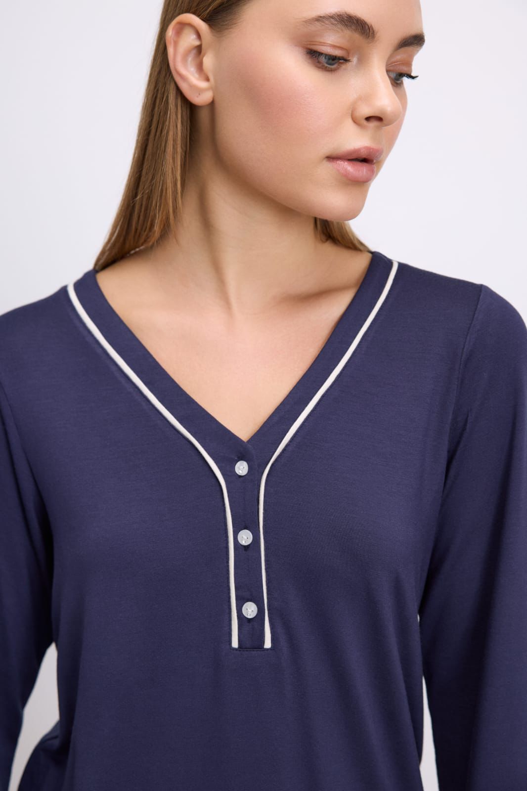 Navy blue long-sleeve shirt with white buttons and trim on a plain background