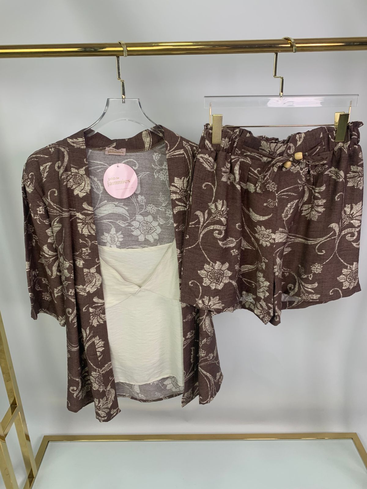 3-piece women’s short pyjama set - pajama set - summer pajama - women pajama - cocoa floral-patterned outfit with a sheer top on a rack.