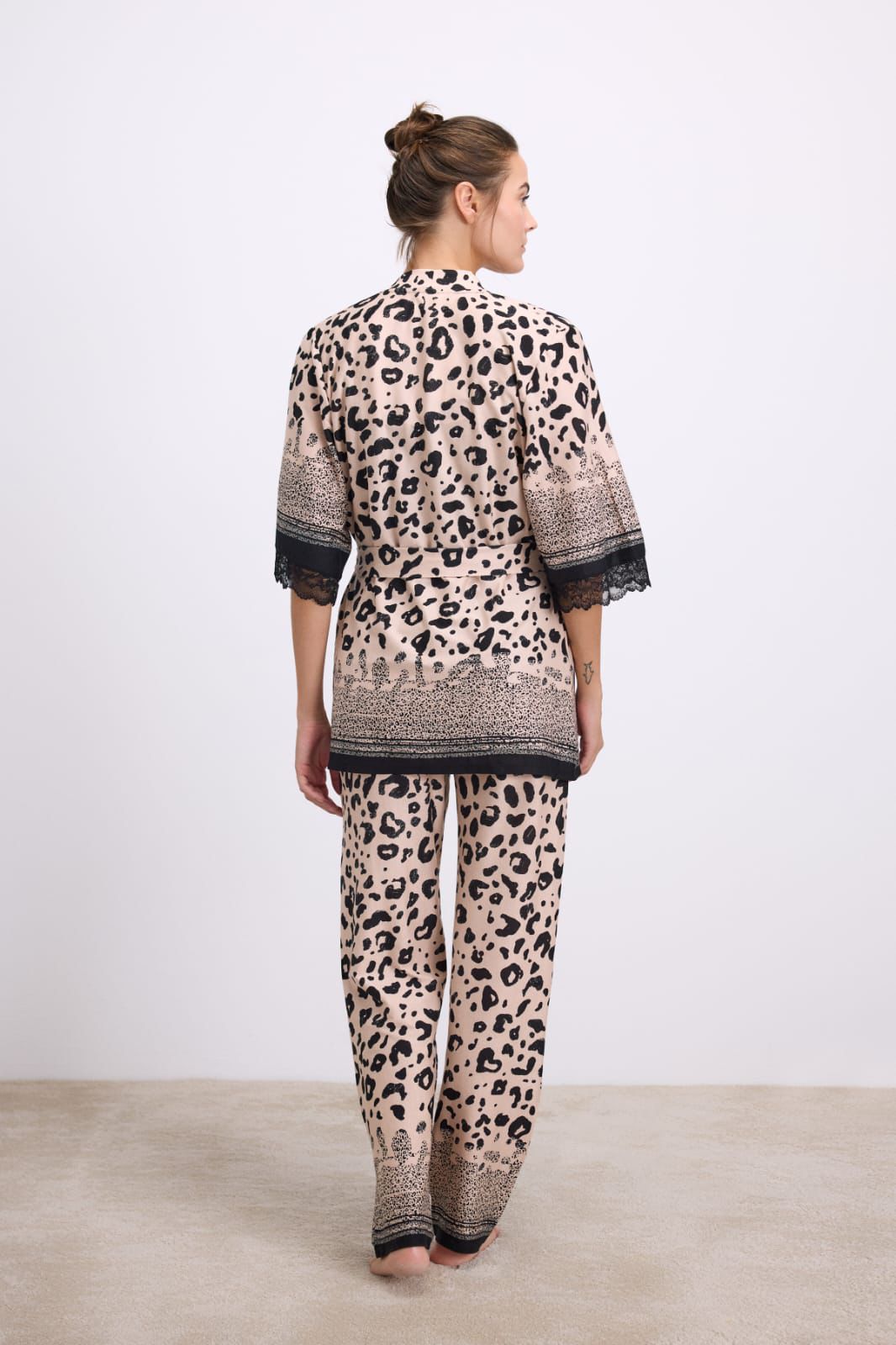 Woman wearing a leopard print outfit with a matching top and pants on a plain background