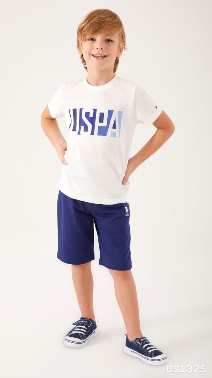 Child wearing Popjammies USPA Graphic Pyjama Set with white top and navy shorts standing with hands on hips