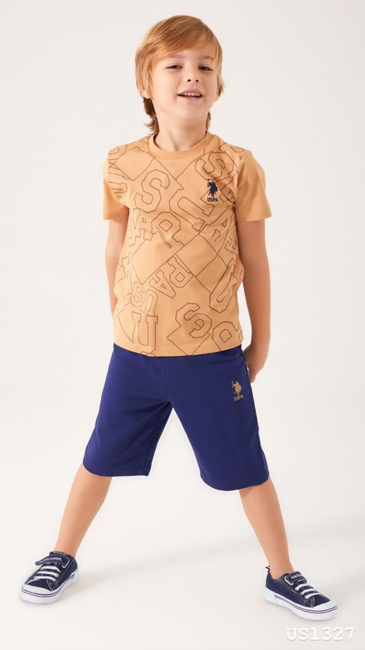 Child wearing Popjammies USPA Graphic Pyjama Set with mustard top and navy shorts standing confidently