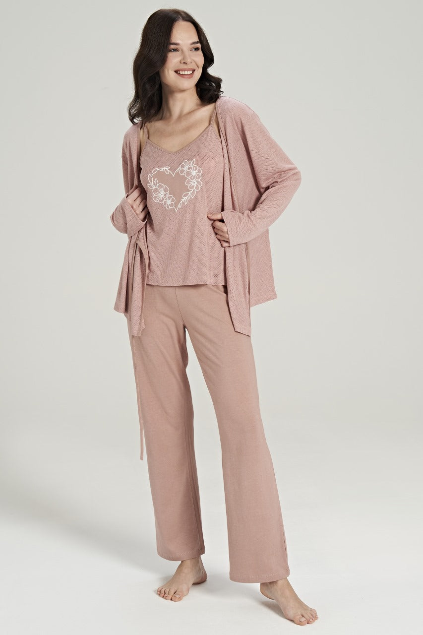 Smiling woman wearing a three-piece pink loungewear set from Popjammies, featuring a spaghetti strap top with a floral heart design, matching relaxed-fit pants, and a cozy long-sleeve cardigan.