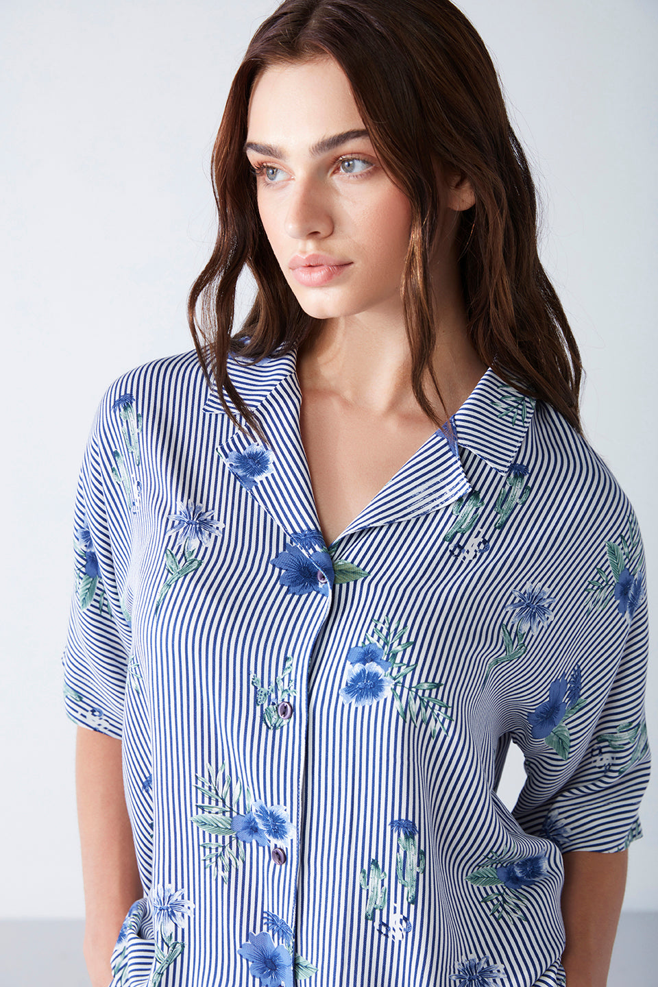 Close-up of a woman in a blue striped floral print pyjama top from Popjammies, showcasing the delicate floral pattern and collared design.
