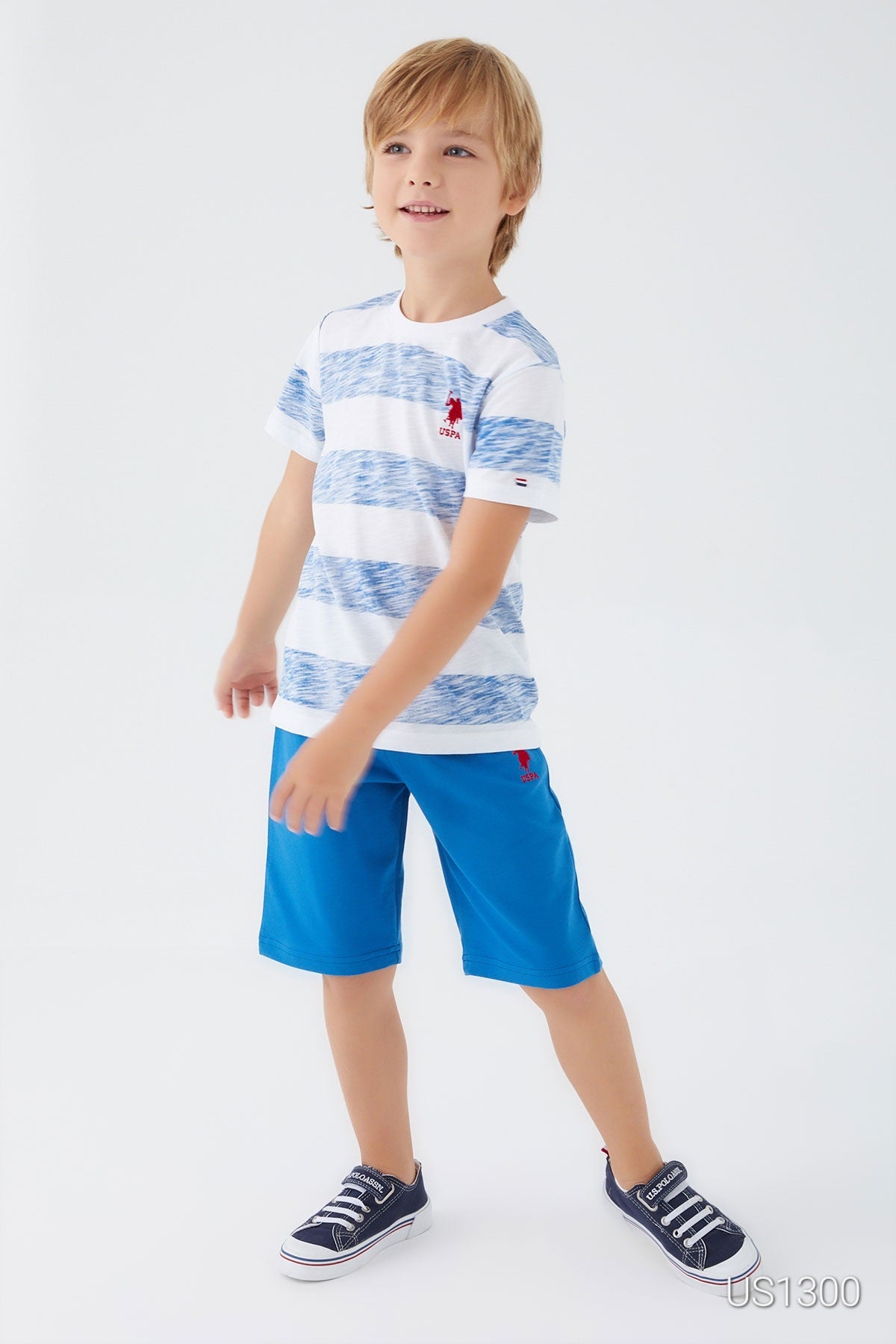 Child posing and wearing Popjammies pyjama set with white top and large light blue patterns, paired with blue shorts 