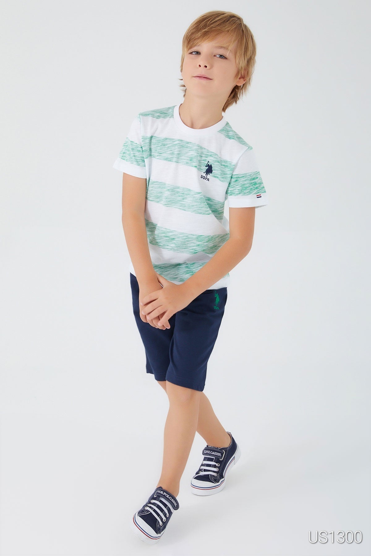 Child posing and wearing Popjammies pyjama set with white top and large green patterns, paired with navy shorts