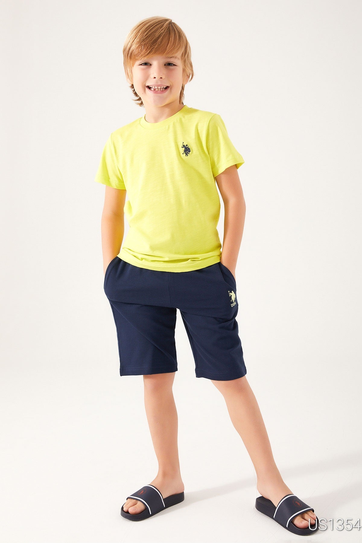 Boy wearing Popjammies Yellow USPA Top and Navy Shorts, standing and smiling.