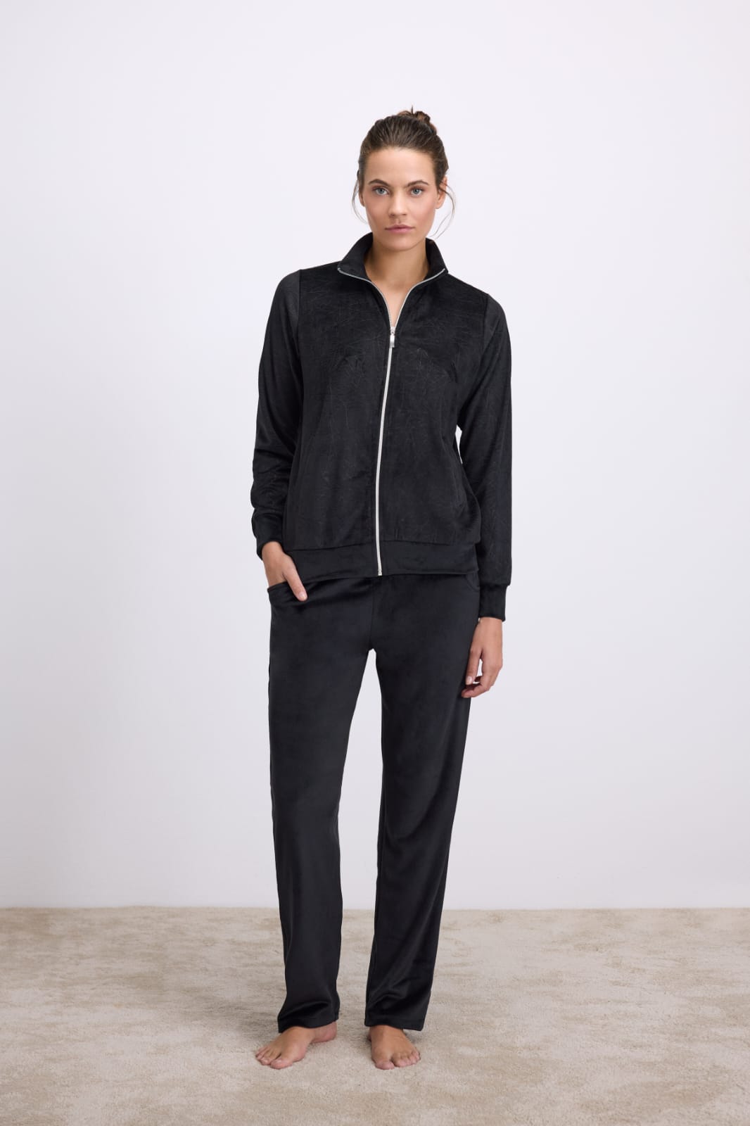 Person wearing a black zip-up hoodie and pants on a white background