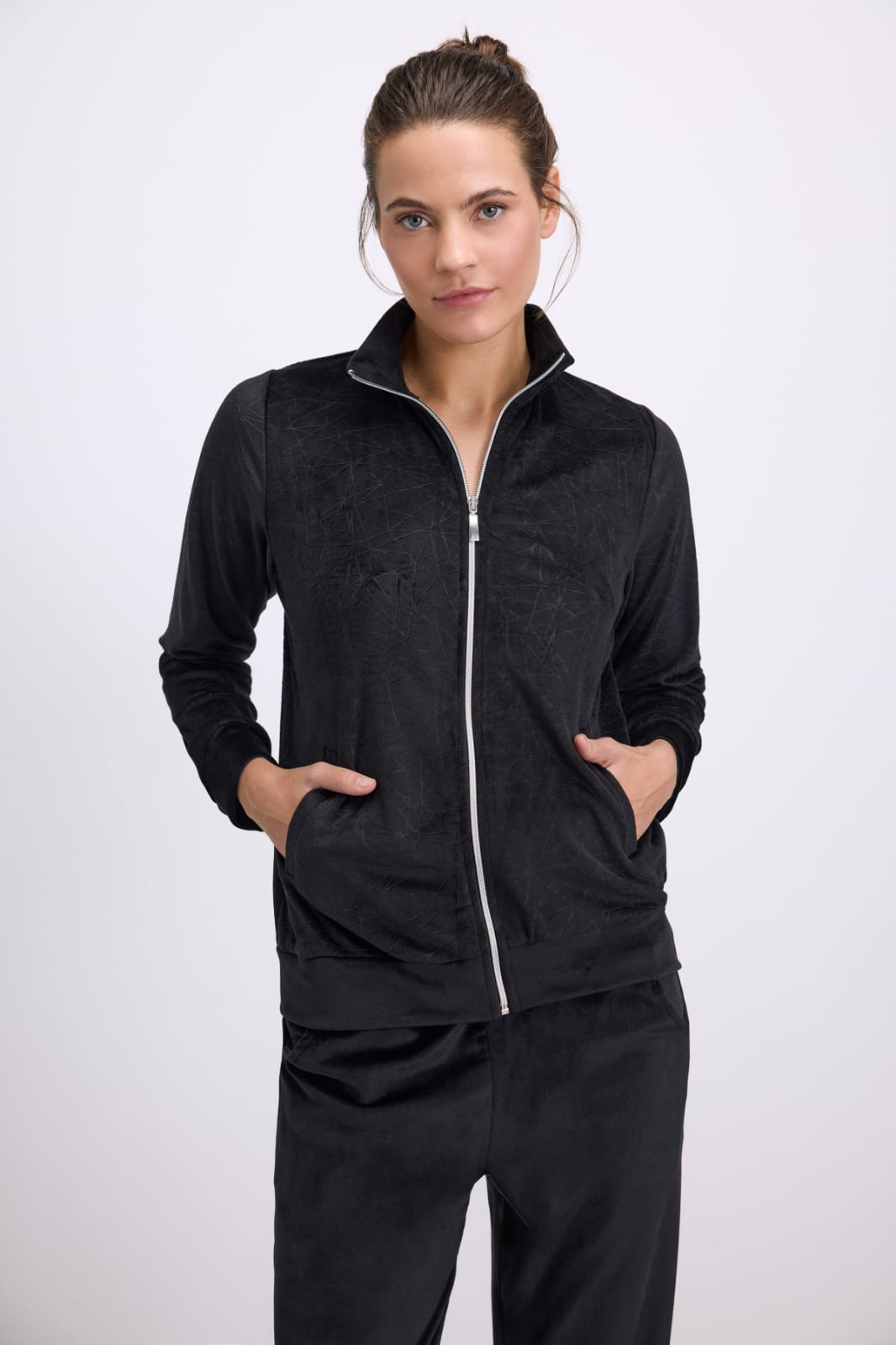 Woman wearing a black tracksuit with a white zipper on a white background