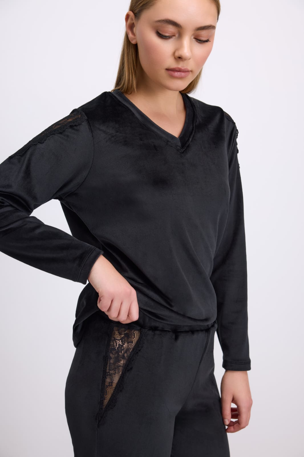 Woman wearing a black long-sleeve top and pants on a white background