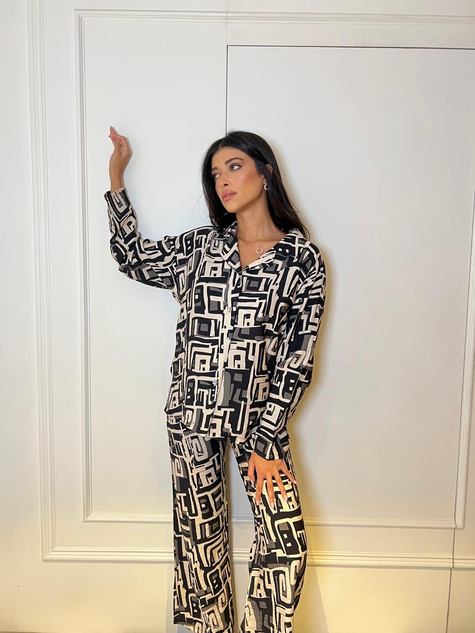 Woman wearing a black and white patterned outfit against a white wall.