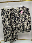 Black and white patterned shirt and pants on hangers against a white background
