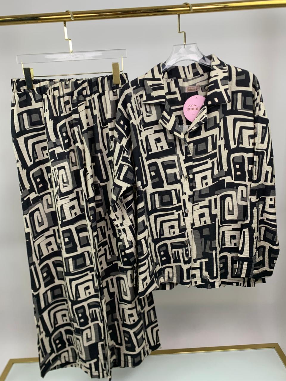 Black and white patterned shirt and pants on hangers against a white background