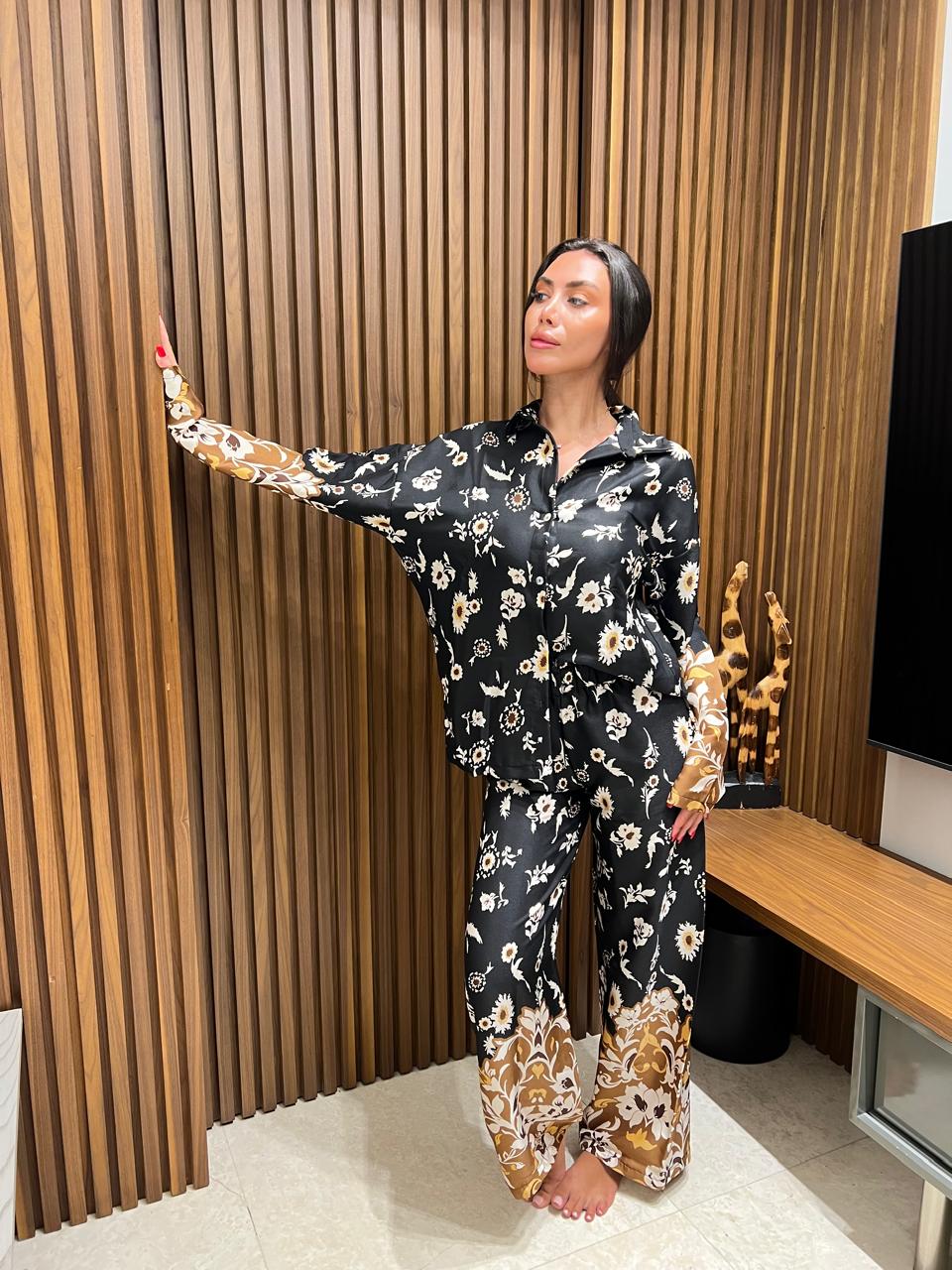 Woman in a floral pajama set standing in a room with wooden paneling.