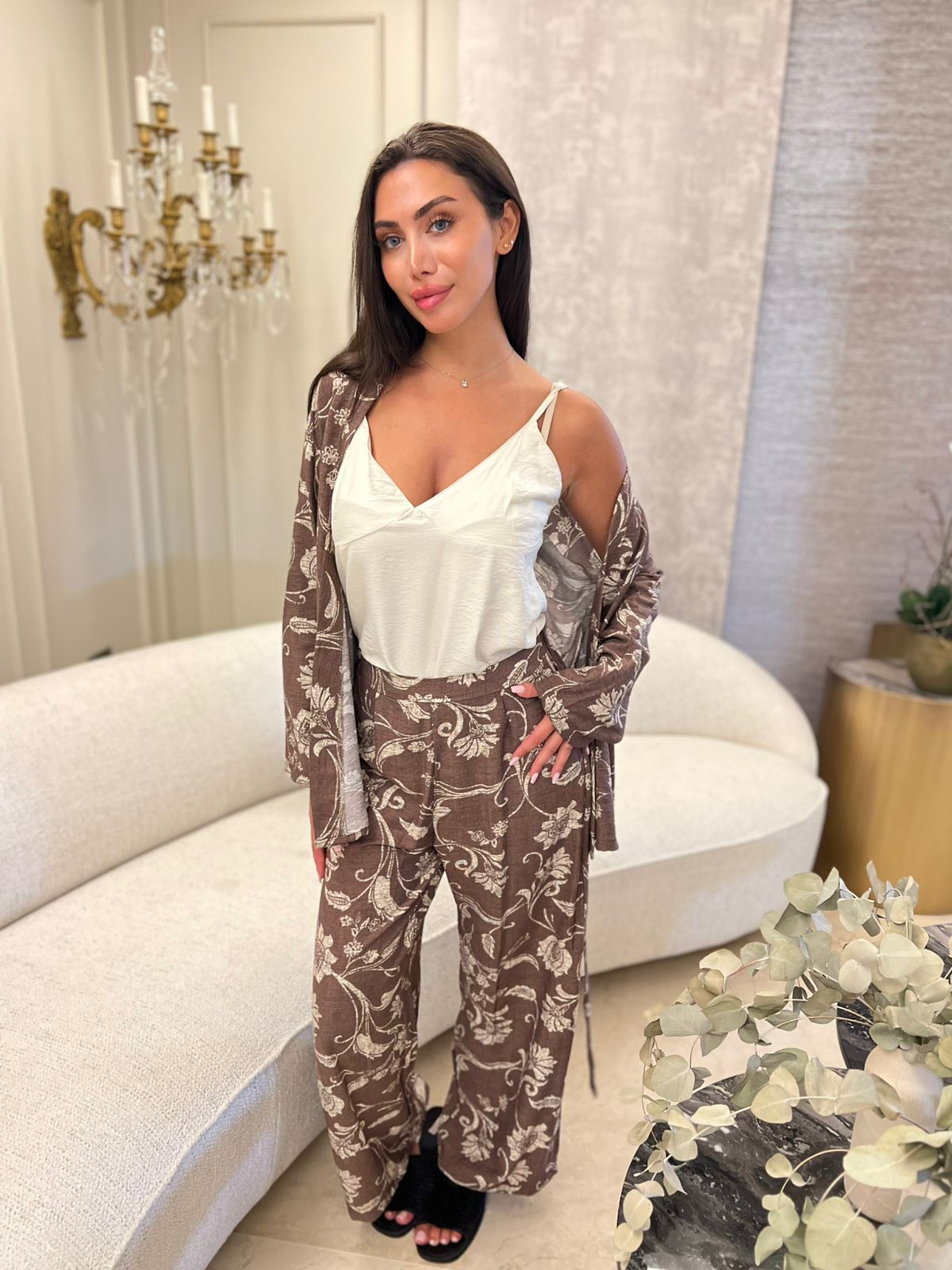 3-piece pants pyjama set - Woman in a stylish outfit standing in an elegant room with a chandelier and white sofa.