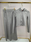 Gray hoodie and pants set on hangers against a white background