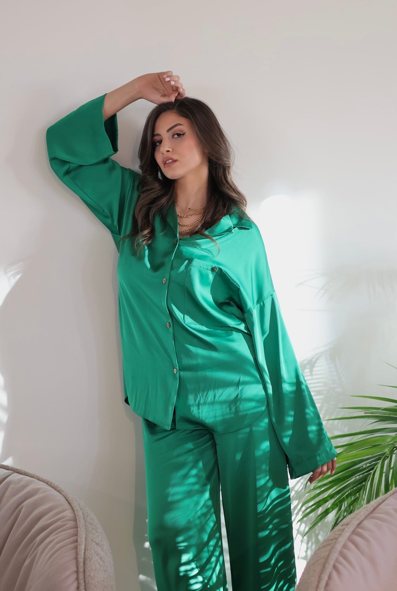 Woman wearing Popjammies Green Satin Pyjama Set, standing stylishly with a relaxed-fit button-up shirt and wide-leg pants, showcasing elegant sleepwear.
