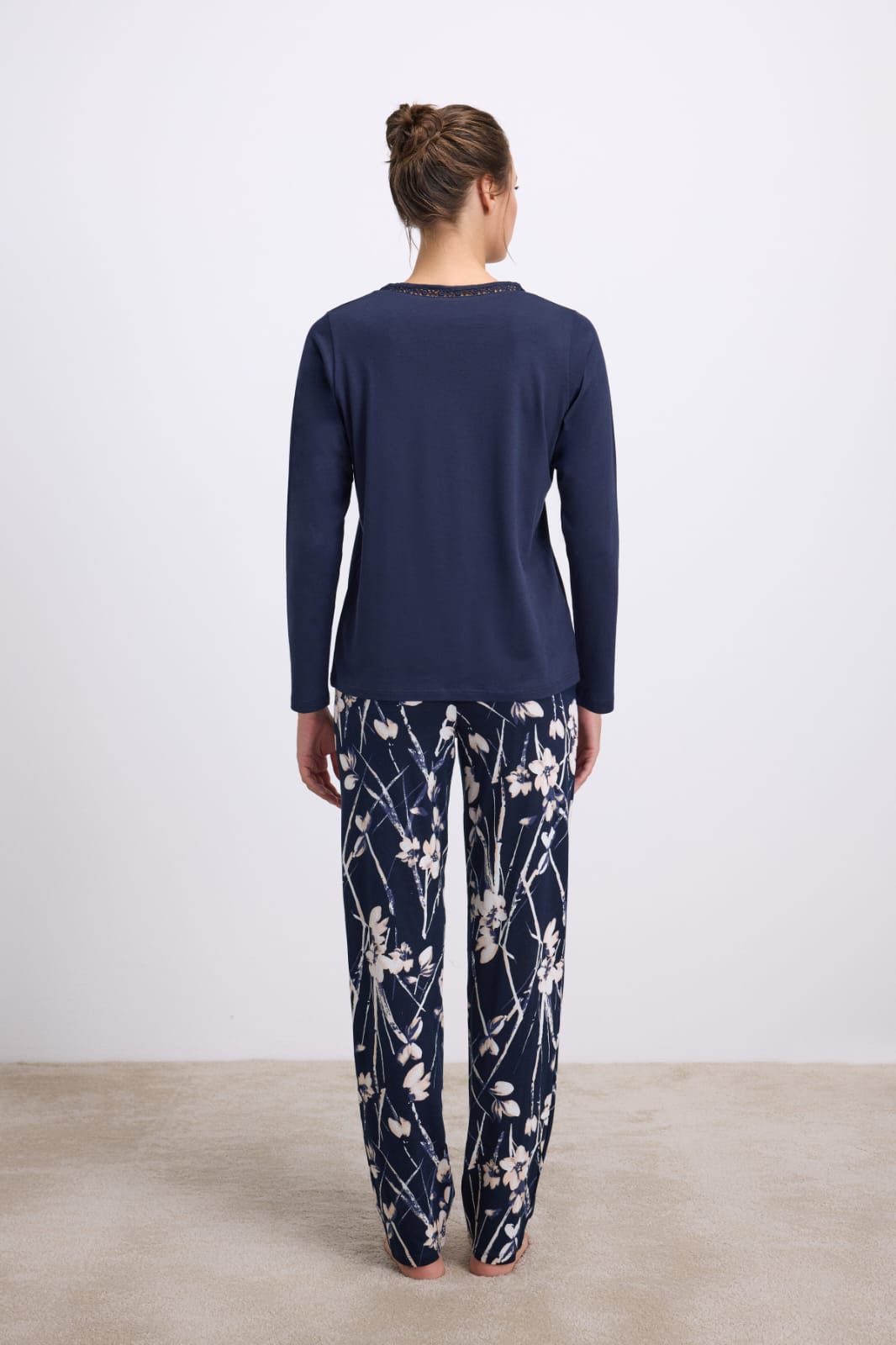 Person wearing navy long-sleeve top and floral pants on a plain background