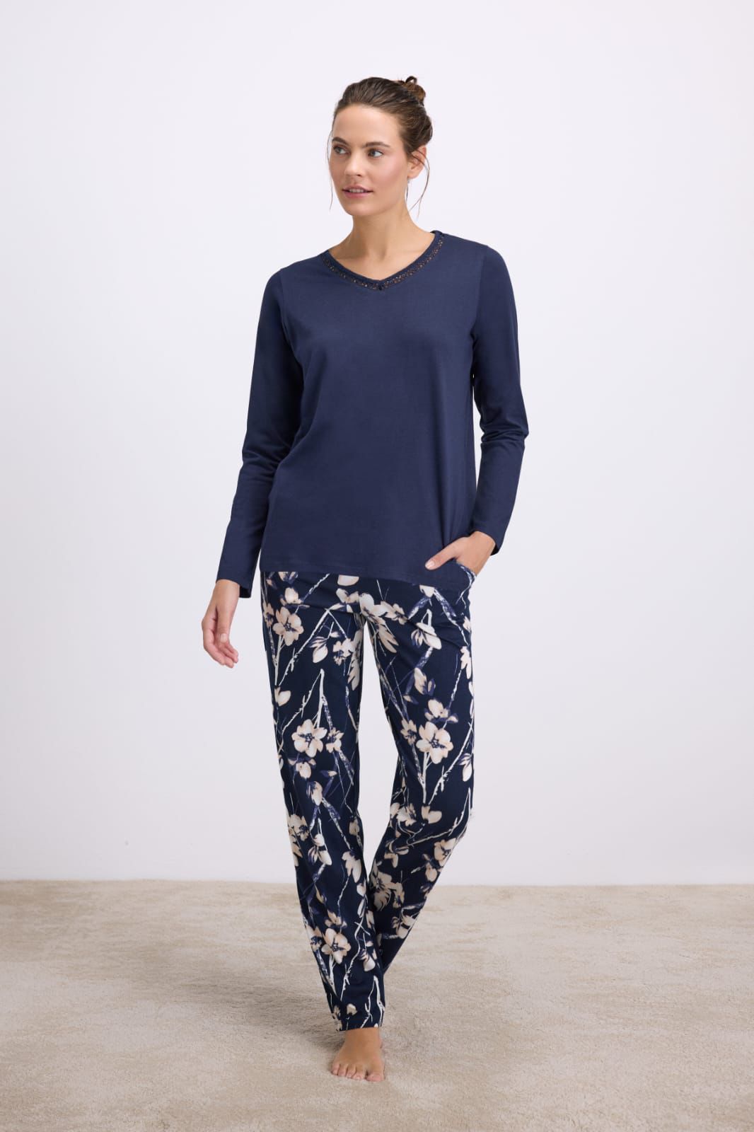 Woman wearing navy blue pajama set with floral pants on a white background
