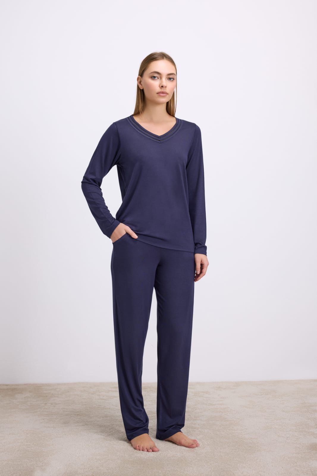 Woman wearing a navy blue pajama set on a plain background