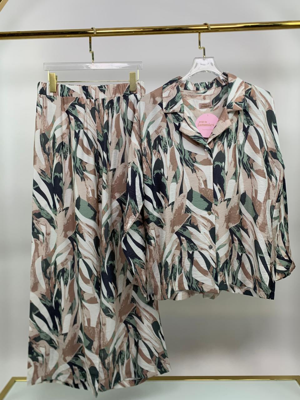 Floral patterned shirt and pants on hangers against a white background