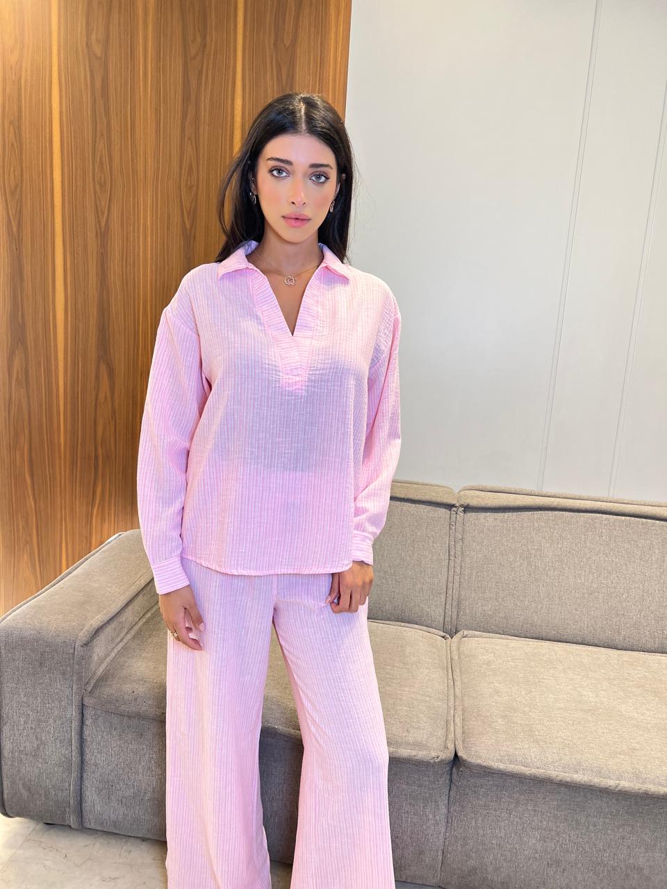 Woman wearing a pink outfit standing in a room with a couch and wooden panel.
2-piece women’s pyjama set featuring a cozy top and matching pants