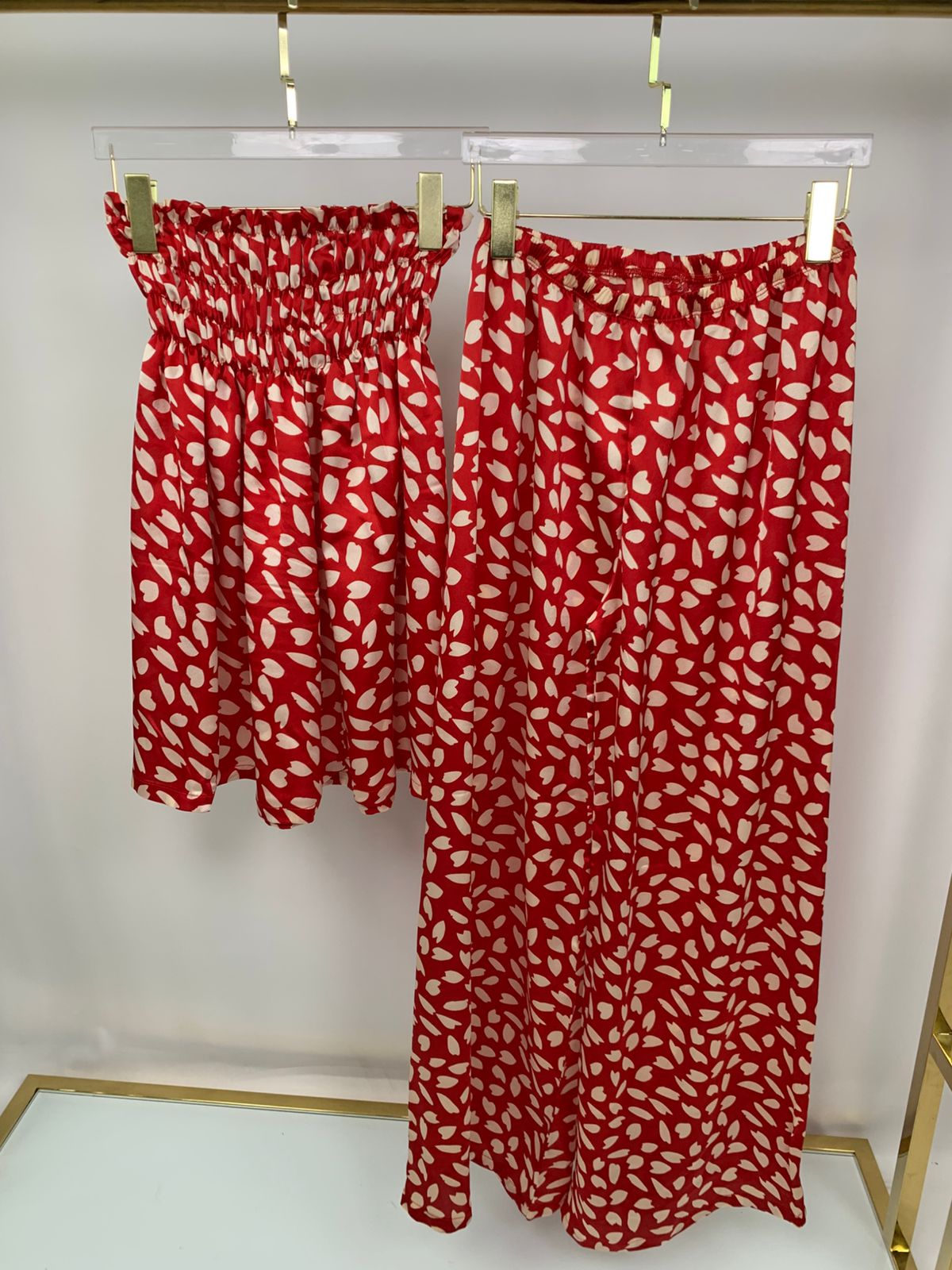 2-piece women’s pants pyjama set - pajama set - summer pajama - women pajama - Red and white patterned skirt hanging on a rack against a white background