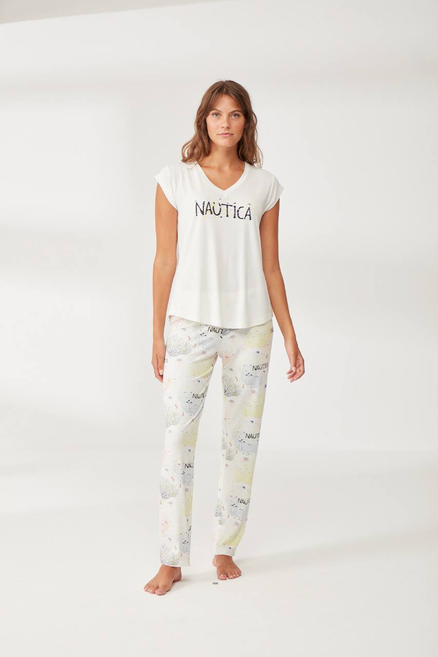 Woman wearing a white V-neck top with a "Nautica" graphic and matching full-length pants with a playful print by Popjammies.