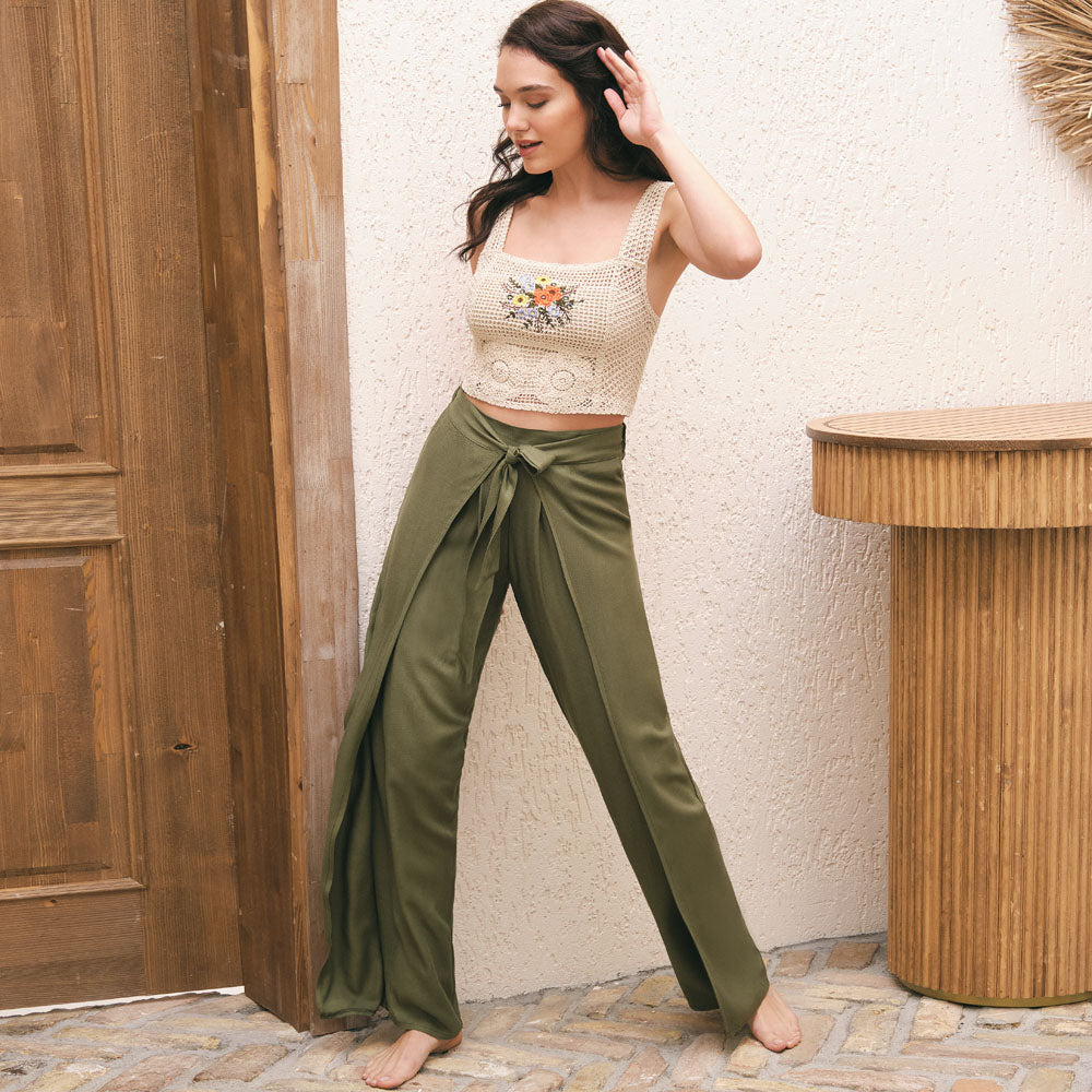 Woman wearing a stylish pajama set with a crochet crop top featuring floral embroidery and flowy olive green pants, from Popjammies.