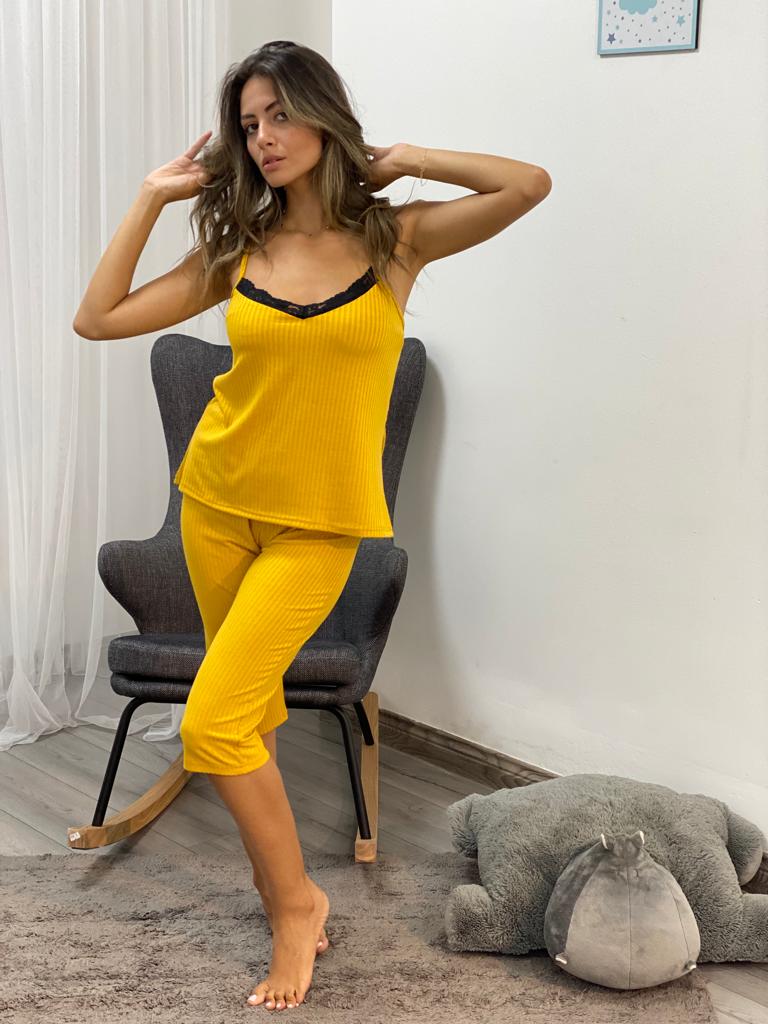 Woman wearing a yellow ribbed camisole top with black lace trim and matching capri pantacour