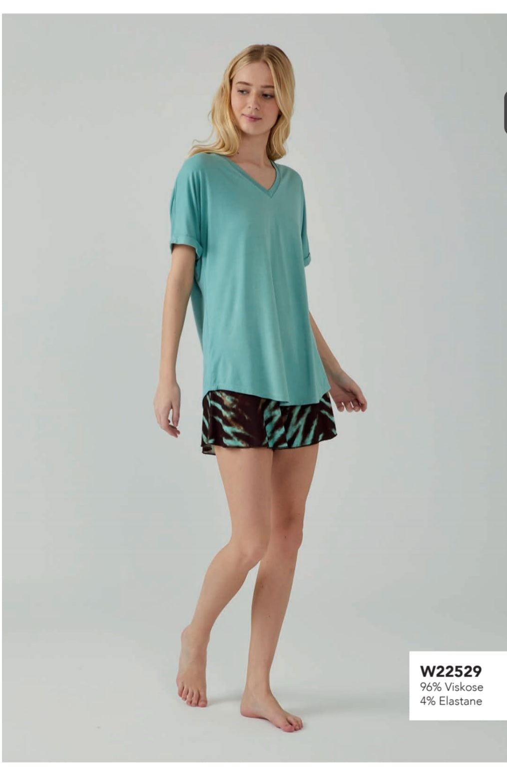 Model wearing Popjammies Aqua Delight Pyjama Set with an aqua V-neck top and turquoise and black tie-dye shorts.