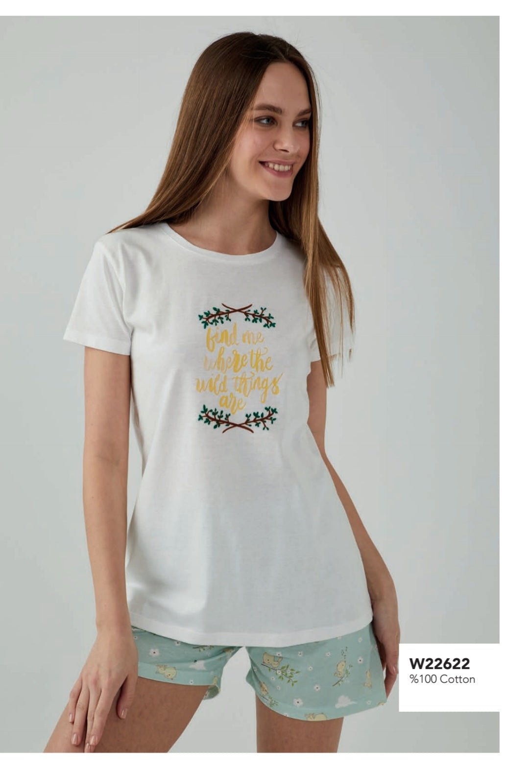  Model wearing the Popjammies Wild Things Pyjama Set, featuring a white top with the phrase "Find me where the wild things are" embroidered in yellow and green, and mint green shorts with a playful forest print.